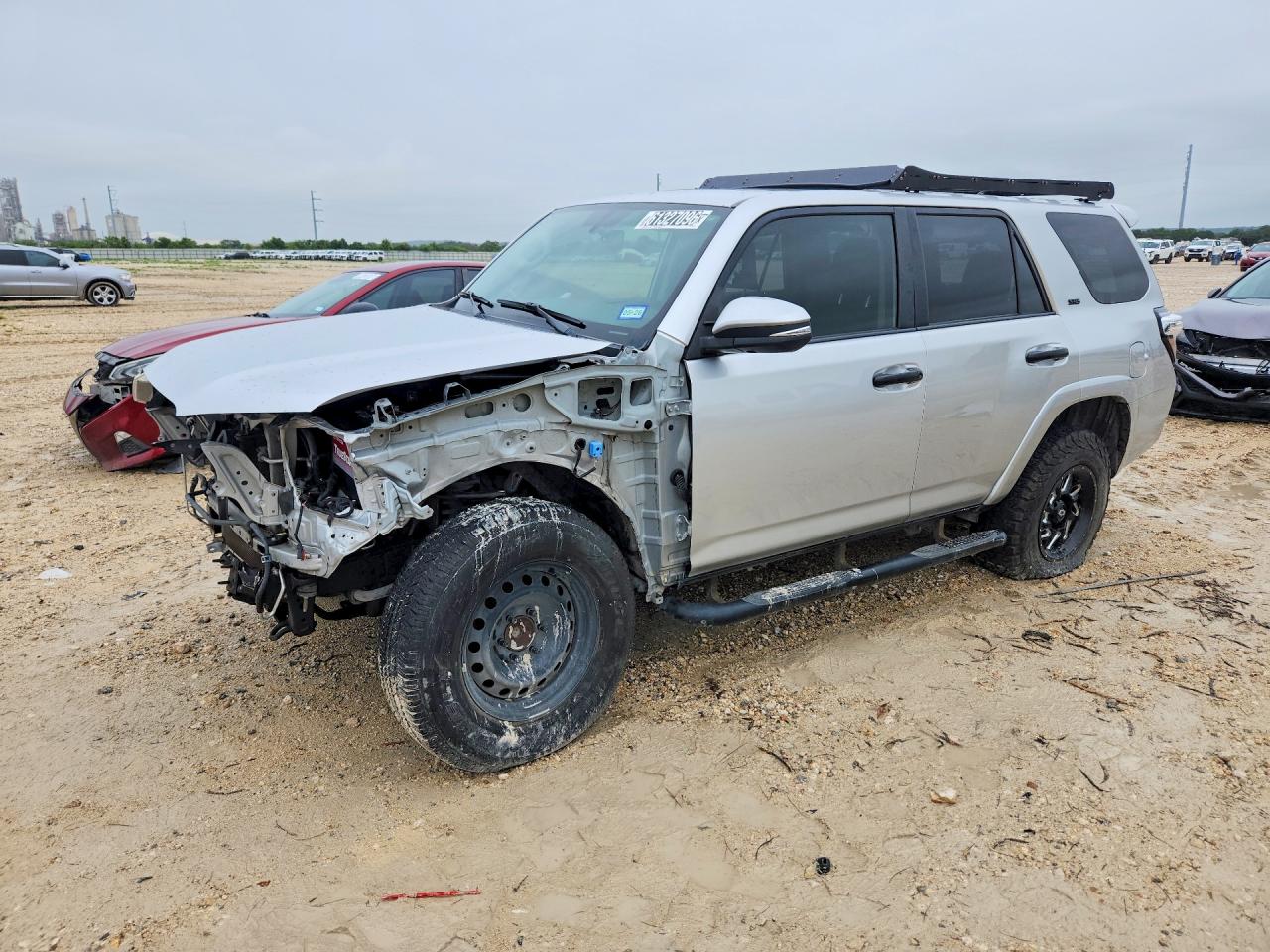A silver 2018 Toyota 4Runner SR5 SUV with front-end collision damage at a salvage yard