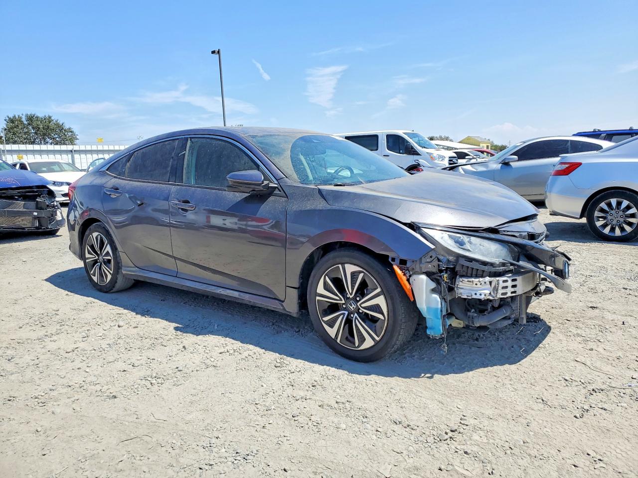 A gray 2019 Honda Civic EX sedan with severe front-end collision damage at a salvage yard