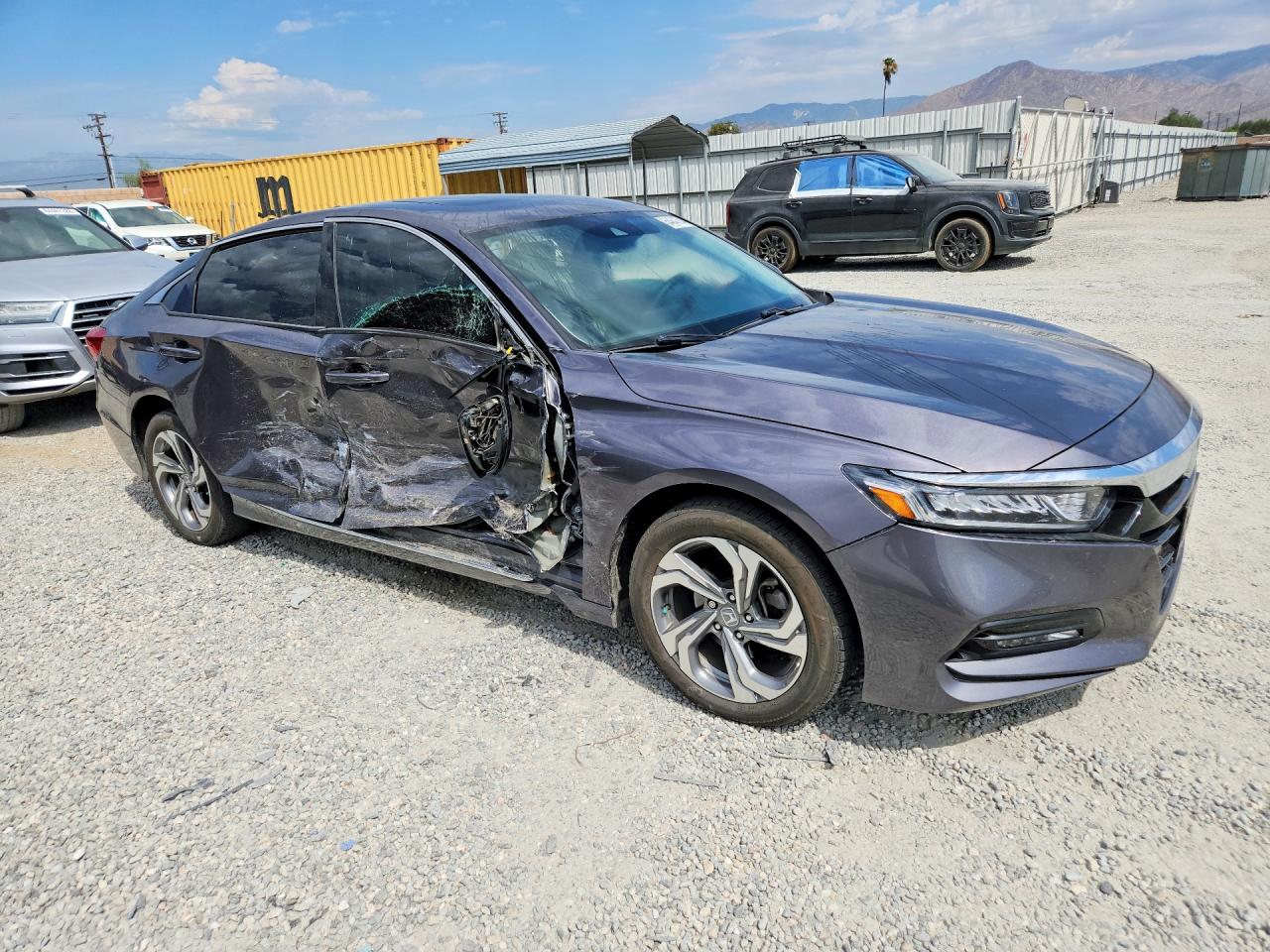 A gray 2019 Honda Accord EX-L sedan with severe driver-side collision damage at a salvage yard