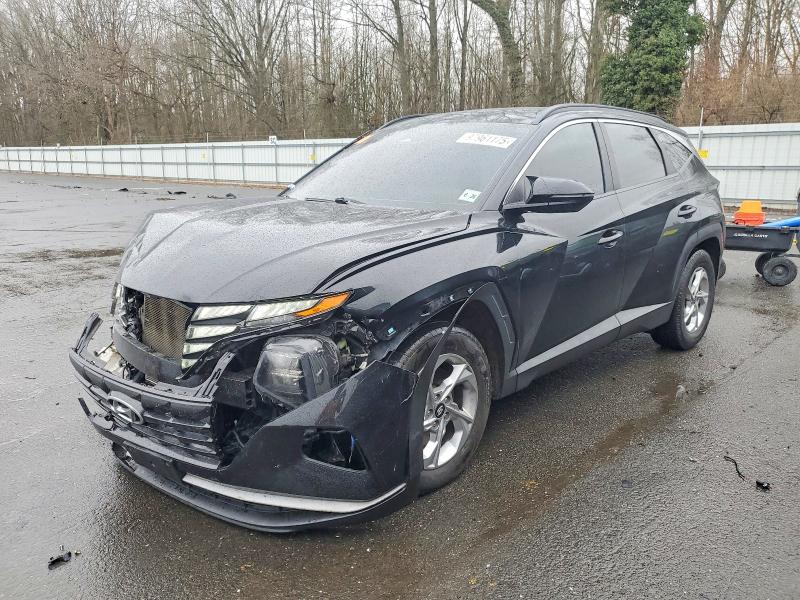 A silver 2021 Hyundai Tucson SEL compact SUV with dented driver side door and scraped paint in a suburban parking lot