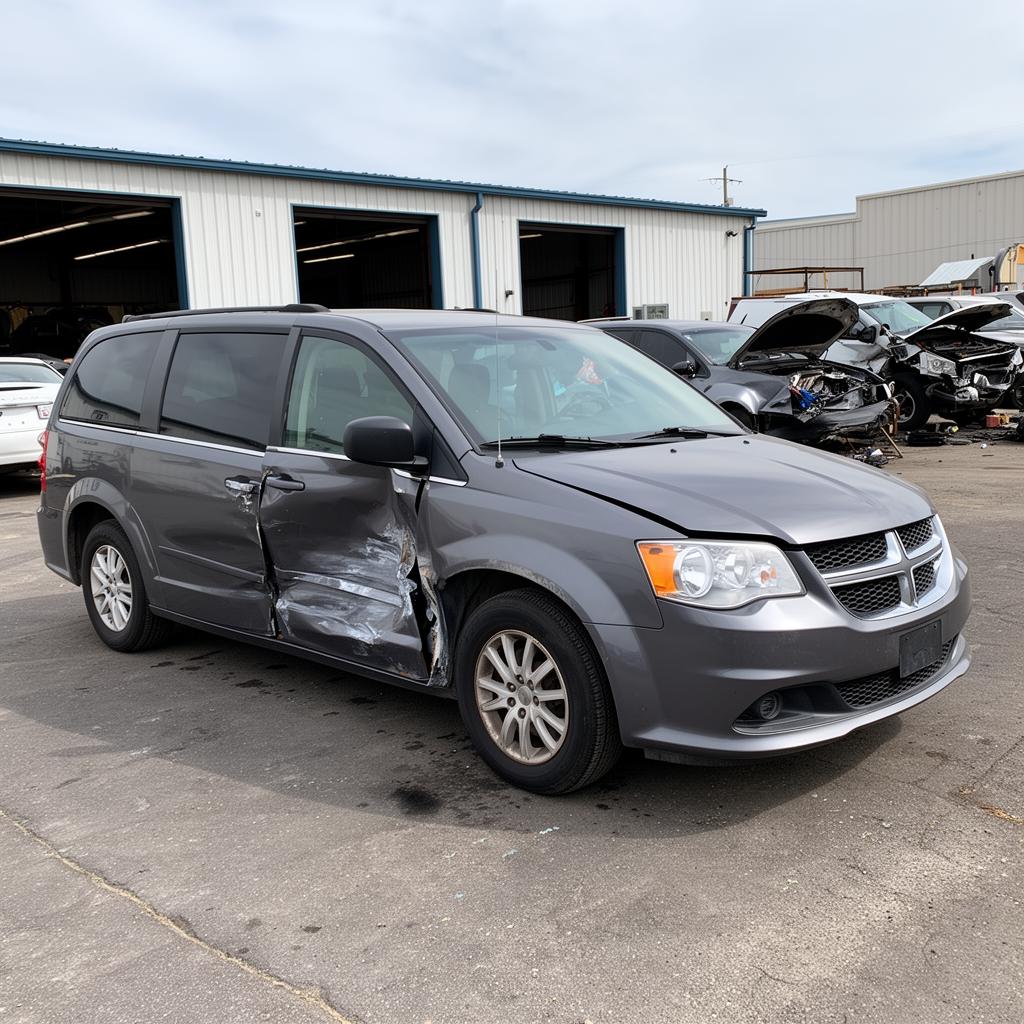 A blue 2017 Chrysler Pacifica minivan with crumpled hood after collision on a suburban street