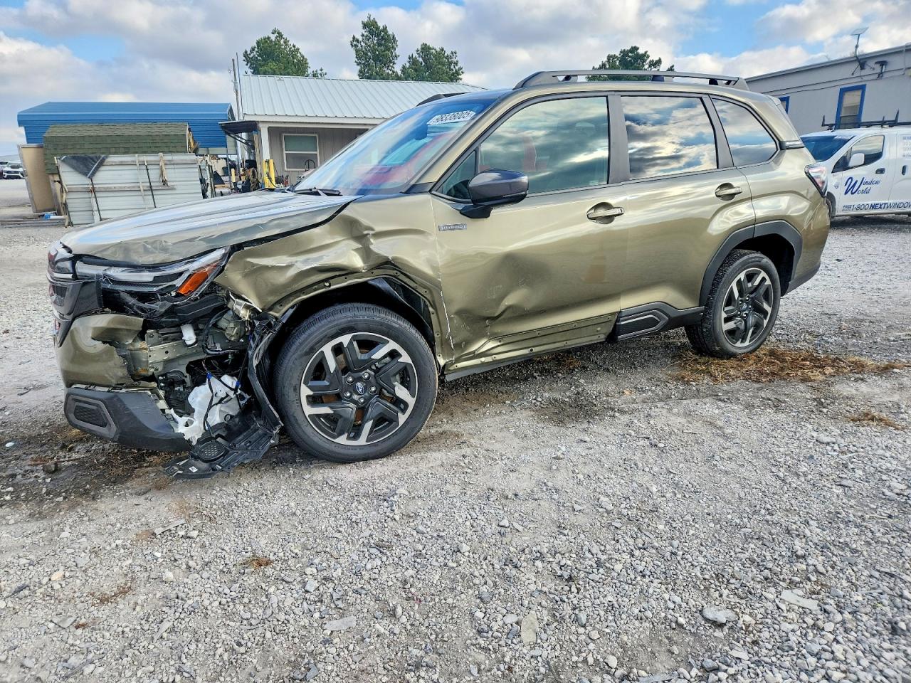 A green 2019 Subaru Forester Premium with front-end damage and shattered headlight parked on a wet street in the rain